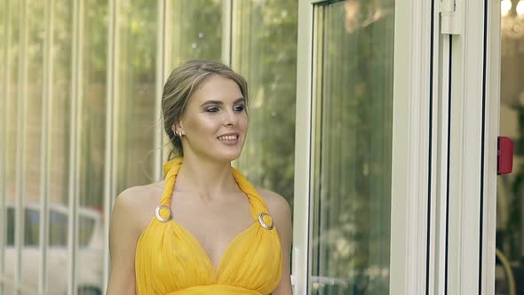 CU Slow Motion Young Beautiful Girl in a Lush Yellow Evening Gown Walks Along the Transparent alt