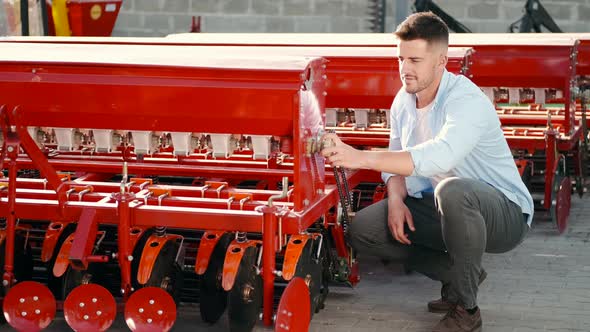 Younf Farmer Choosing Spare Part for Agriculture Machinery alt