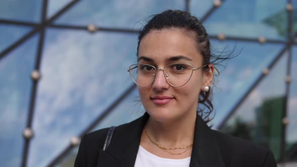 Portrait of Smiling Confident Brunette Business Woman Looking at Camera in Front of Office Building alt