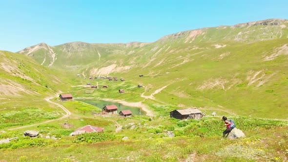 Hiker Sit Enjoy View Of Village In Caucasus