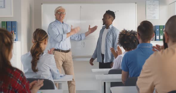 Diverse Students Group Applauding to African Classmate Standing Near White Board with Professor alt