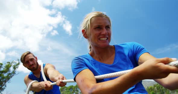 Fit people playing tug of war during obstacle training course 4k alt