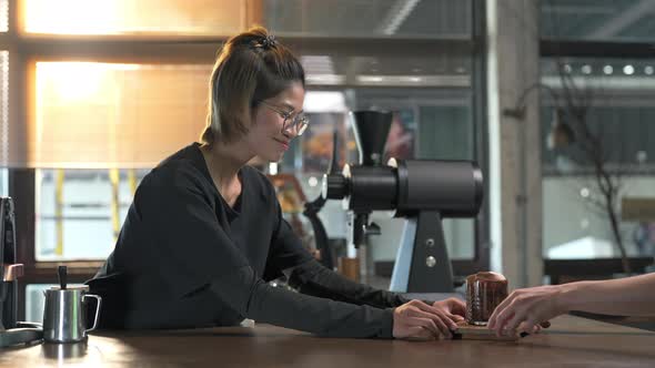 4K Asian woman barista serving iced chocolate with froth milk to customer alt