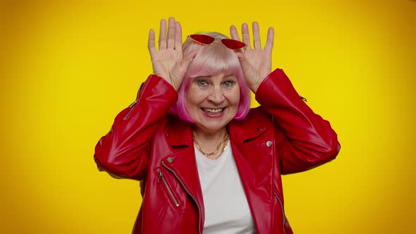 Funny Silly Senior Old Granny Woman Smiling Friendly and Doing Bunny Ears Gesture on Head Fooling alt