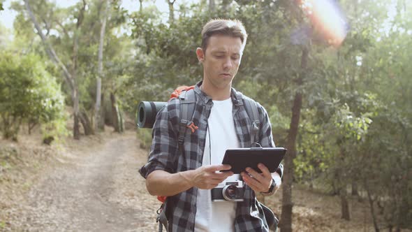 Focused Male Backpackers Walking in Forest alt