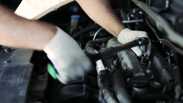 Male Auto Mechanic Changes Spark Plugs in a Car Engine