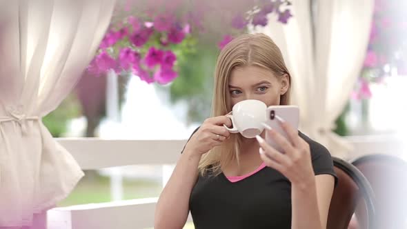 Smiling girl spending time in a street cafe using digital tablet alt