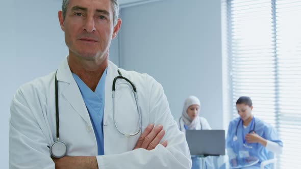 Close-up of Caucasian male doctor standing with arms crossed in hospital alt