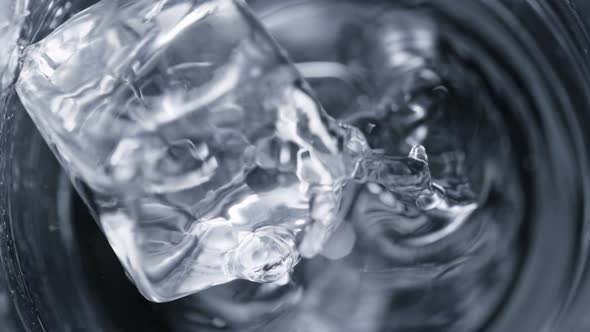 Super Slow Motion Detail Shot of Ice Cube Falling Into Glass With Alcohol Liquid at 1000 Fps alt