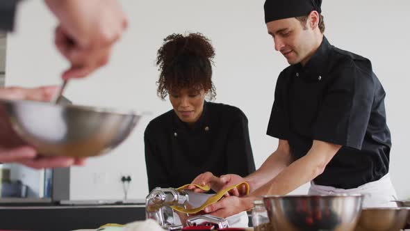 Diverse group of chefs preparing dishes and smiling in a kitchen alt