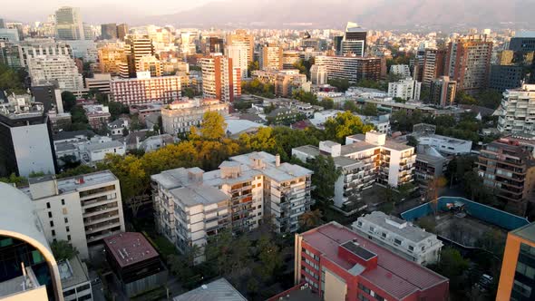 Aerial dolly out of buildings in residential neighborhood surrounded by trees, hills in background a alt