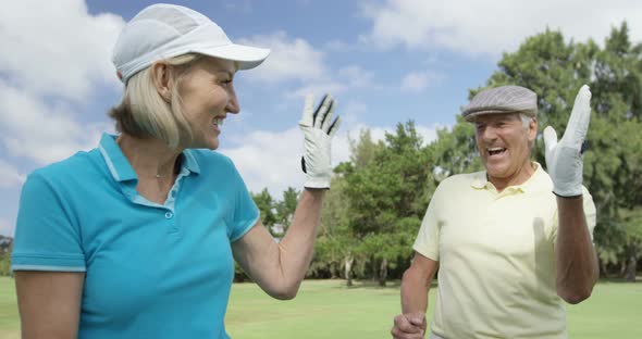 Two happy golfers giving high five alt