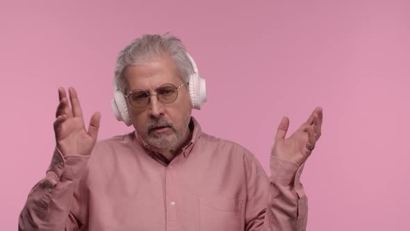 Portrait of an Elderly Man with Glasses Dancing and Enjoying Music in Big White Headphones alt