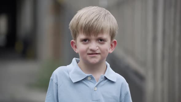 Slow motion of young boy with cleft lip standing and smiling. alt