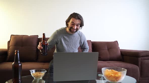 Young Attractive Caucasian Man Celebrating Birthday Online with Bottle of Beer alt
