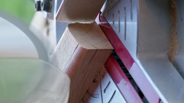 Vertical Shot Woodworker Cuts Oak Workpiece on Mitre Saw Diagonally Angle 30 Degrees Closeup