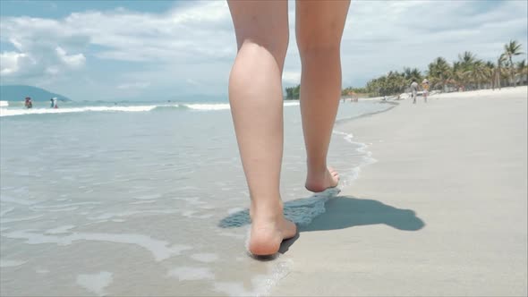 On a Tropical Beach of Women's Legs European Cute Brunette Goes Under the Hot Summer Sun Along the alt