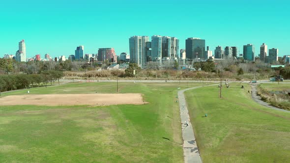 Man walking, jogging, City Park, grass towers and buildings, skyline, crane down. Vicente Lopez, Bue alt