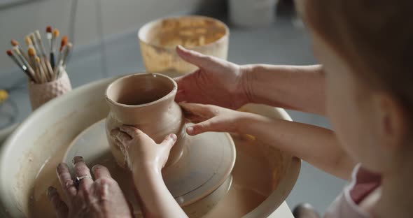 Grandmother Teaches Her Granddaughter Working on a Pottery Rotating Wheel