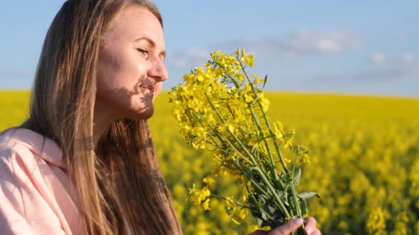 Young Beautiful Girl Holding a Yellow Bouquet on a Rapeseed Field alt