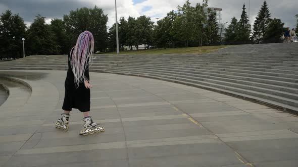 A Young Woman with Multicolored Pigtails Professionally Skates on Roller Skates