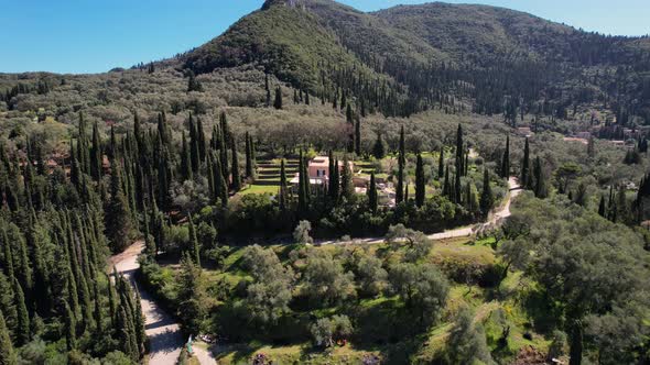 Counter clockwise rotating shot of small, colorful house in between cypresses of the forest covered alt