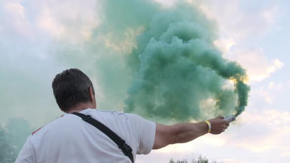 Man Having Fun with Colorful Smoke Flares Against the Sky. Slow Motion alt