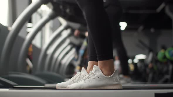 Closeup of Legs Woman Jogging on Treadmill in Gym Side View alt