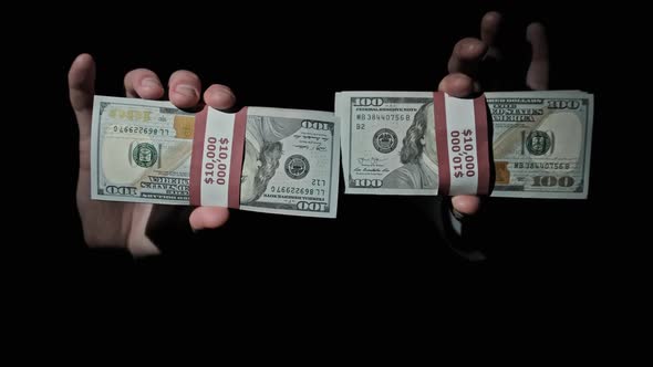 Two Stacks of 10000 American Dollars Bundles in Male Hands on Black Background alt
