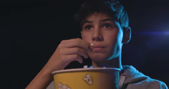 Boy watching a movie at the cinema and eating popcorn, entertainment concept