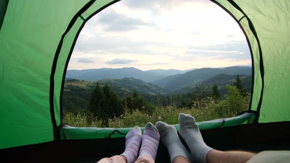 The feet of travelers rest, the couple lies and admires the mountains after climbing alt