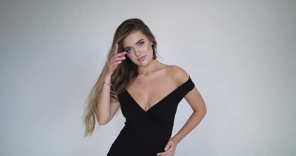 A Young Attractive Girl Runs Her Hand Through Her Hair Without Looking Away From the Camera alt