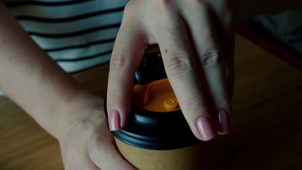 A Woman's Hand with a Pose Manicure on Her Fingers Occupies a Paper Cup with a Coffee Drink and alt