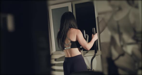 Rear View of Sports Woman Working Out on an Exercise Spin Bike in a Gym alt