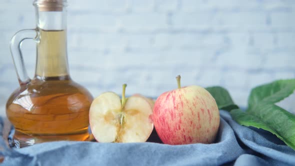 Apple Vinegar in Glass Bottle with Fresh Green Apple on Table alt
