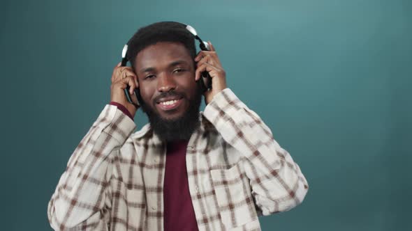 An African Young Man in a White Shirt is Listening to Music and Dancing alt
