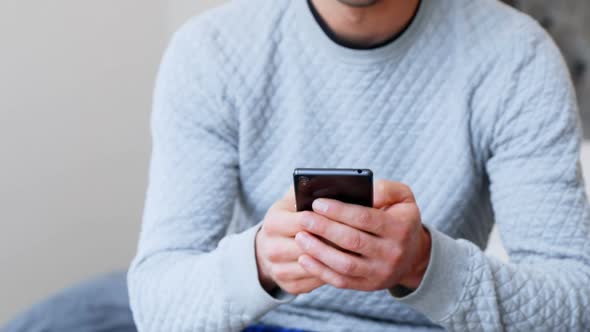 Man using mobile phone in bedroom alt