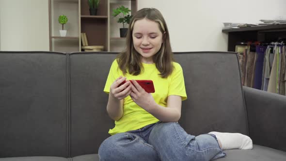 Happy Teen Girl Holding Cell Phone Using Smartphone Device at Home alt