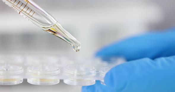 Scientist Chemist Dripping Yellow Liquid From Pipette Into Container  Movie alt