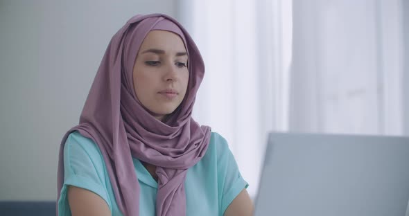 Muslim Woman Working on a Laptop in the Office with Her Christian Coworkers. Closeup Portrait of alt