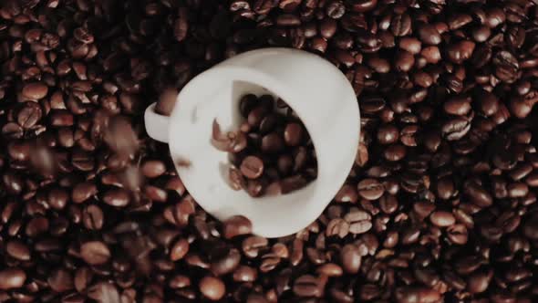 On Top of the Black Roasted Coffee Beans is a White Cup for Flavored Coffee