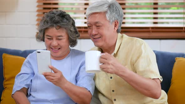 Asian senior couple having video chat using a smartphone and sharing social media.