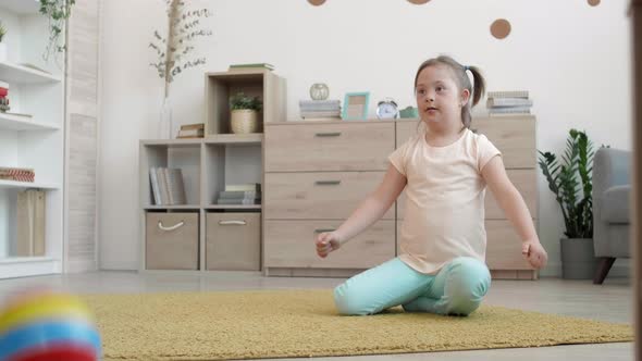 Cheerful Handicapped Girl Playing with Ball in Living Room alt