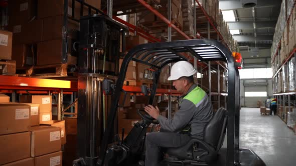 Forklift Truck Operator During Work in Storehouse alt