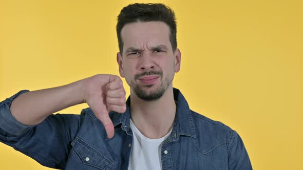 Portrait of Young Man Doing Thumbs Down, Yellow Background alt