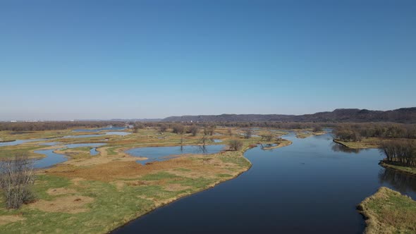 Flyover of meandering river in midwest with patchy islands here and there. Bright autumn day.