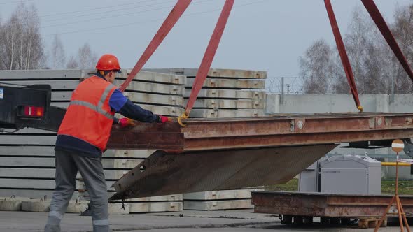Slinger in Helmet and Vest Supervises Unloading at Construction Site