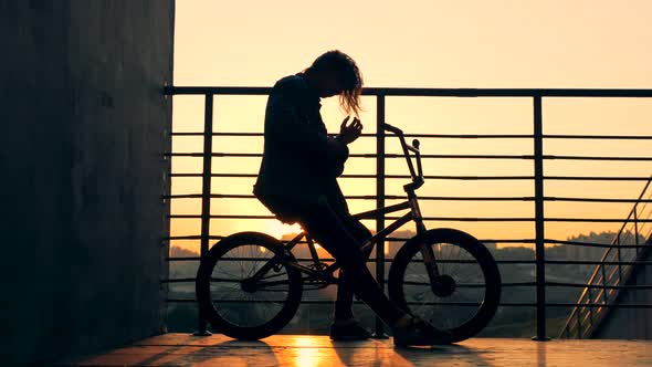 A Person Sits on a Bicycle on a Sunset Background alt