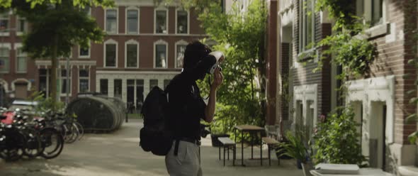 Caucasian man taking photos of building in the city alt
