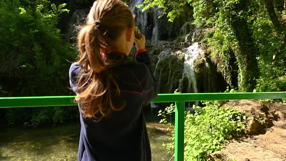 Girl is taking pictures of a beautiful waterfall alt